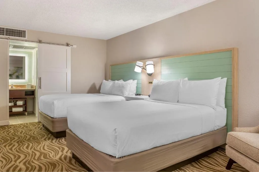 Dos camas con cabecera verde y puerta corrediza de ba&ntilde;o en Wyndham Garden Lake Buena Vista