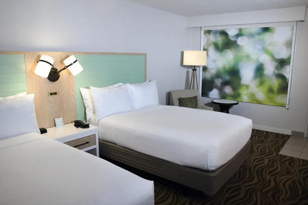 Dos camas con cabeceros de color verde azulado y un sillón en Wyndham Garden Lake Buena Vista