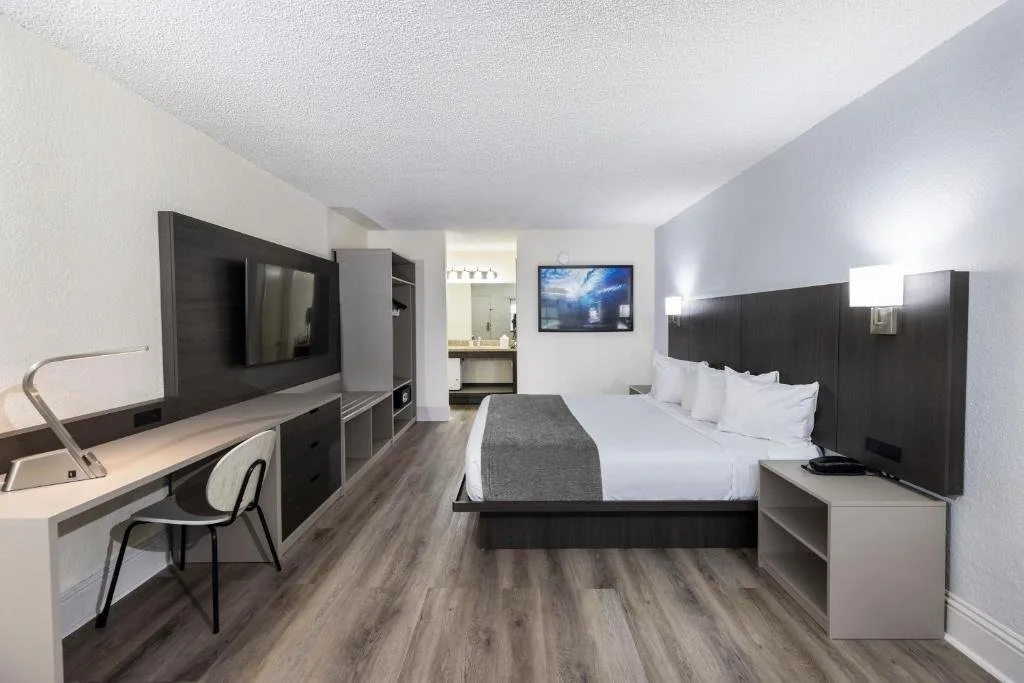 Habitación con cama king, escritorio, TV de pared y suelo de madera en Avanti International Resort