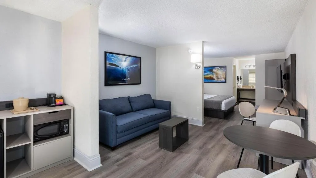 Sala de estar con sof&aacute; azul, microondas, mesa de comedor y cama m&aacute;s all&aacute; en Avanti International Resort