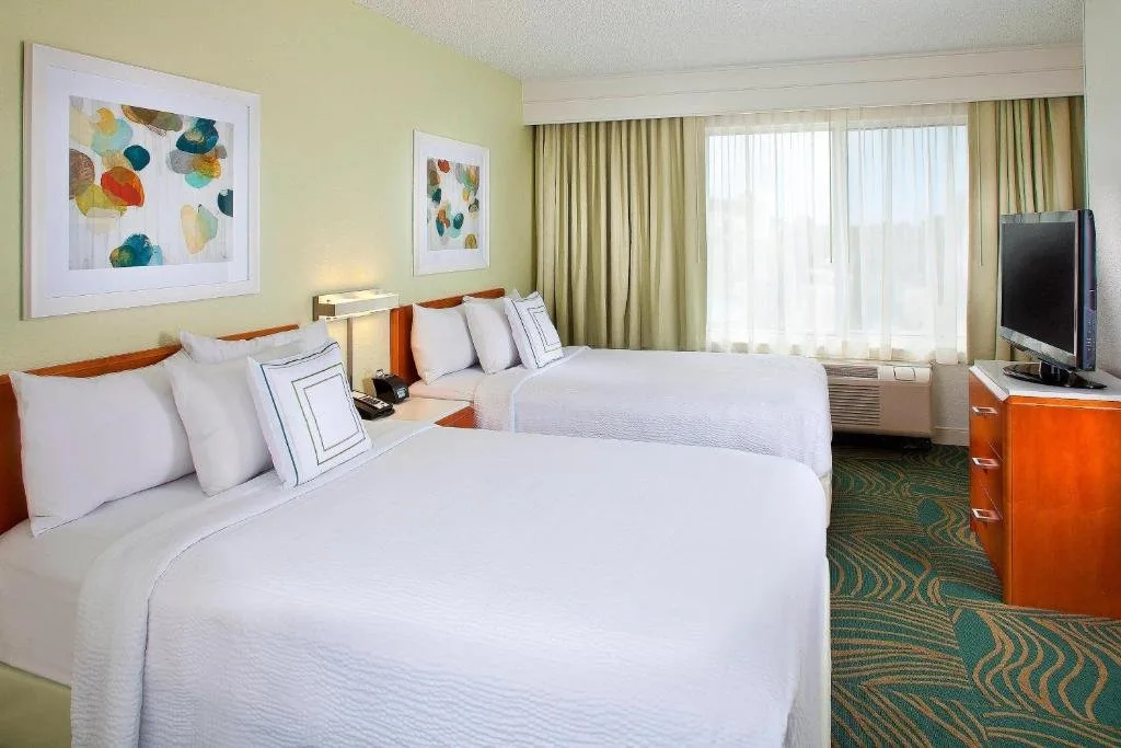 Dos camas, arte mural colorido y un televisor en SpringHill Suites Orlando Lake Buena Vista