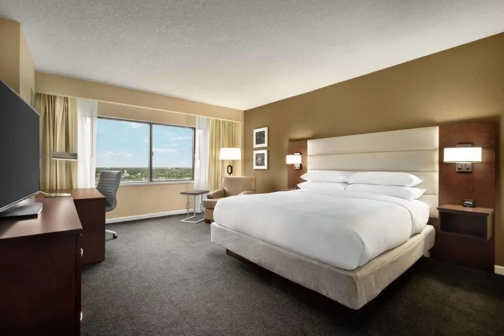Habitaci&oacute;n con cama king y escritorio, sill&oacute;n y ventana con vistas a las copas de los &aacute;rboles en DoubleTree by Hilton Orlando Downtown
