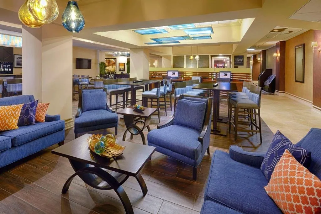 Sal&oacute;n del vest&iacute;bulo con sof&aacute;s azules, sillones y mesas altas en DoubleTree by Hilton Orlando Downtown