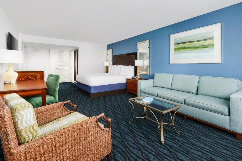 Habitaci&oacute;n con cama, sof&aacute; azul claro y sill&oacute;n de mimbre en CoCo Key Hotel