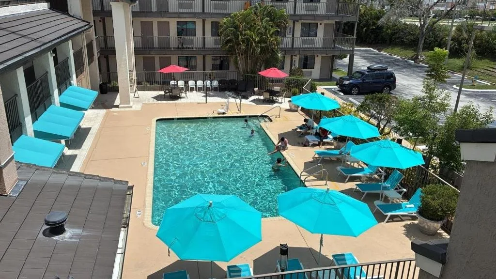 Piscina al aire libre con sombrillas y tumbonas de color turquesa en Quality Inn & Suites By the Parks
