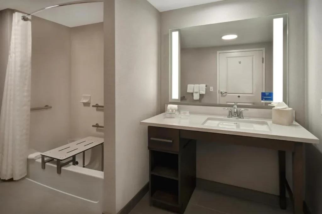 Accessible bathroom with grab bars and a tub transfer bench at Homewood Suites Flamingo Crossings
