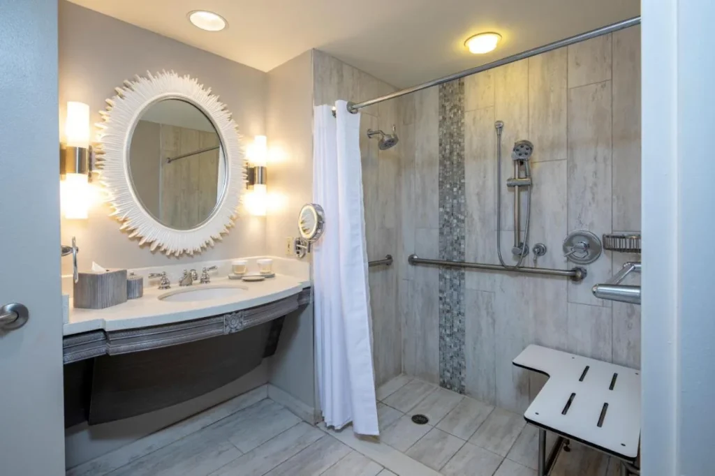 Ba&ntilde;o accesible con ducha sin barreras, asiento plegable y barras de apoyo en el Loews Royal Pacific Resort