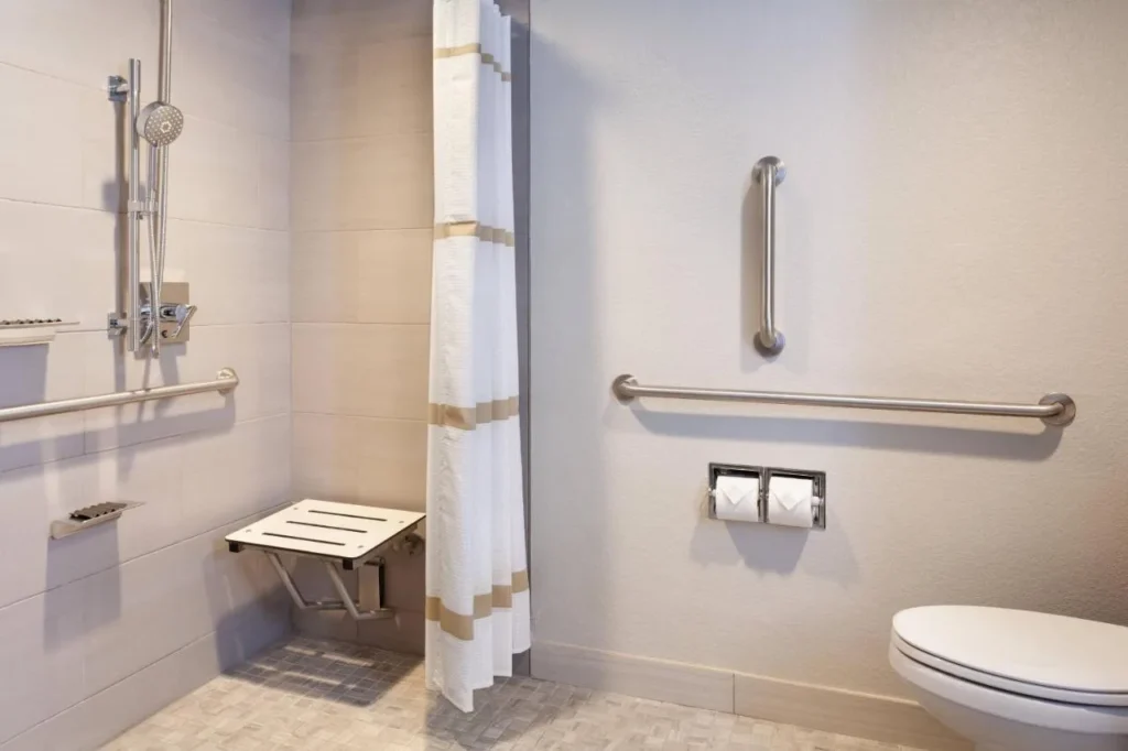 Ba&ntilde;o accesible con ducha con roll-in, asiento plegable y barras de apoyo en el Marriott Orlando Airport Lakeside