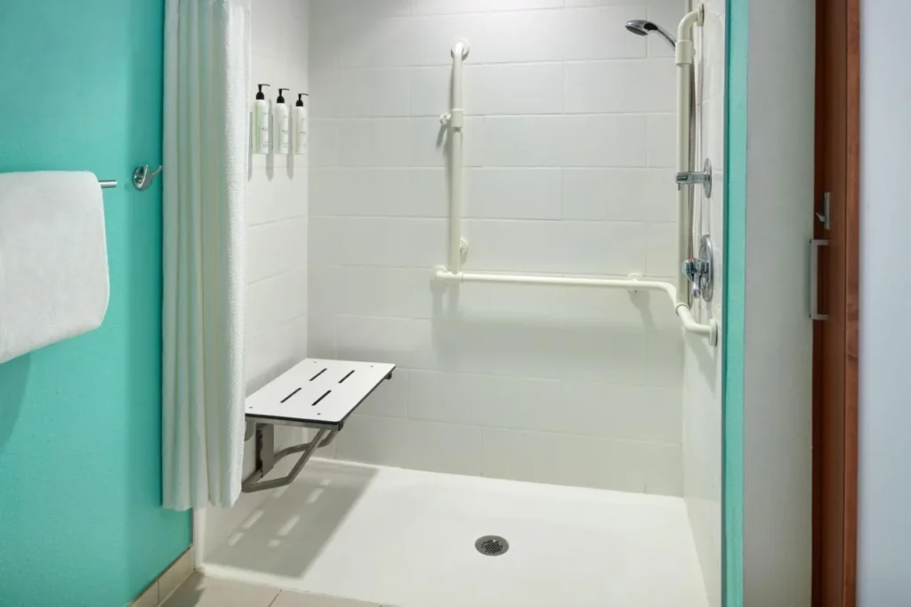 Accessible roll-in shower with fold-down seat and grab bars at SpringHill Suites Orlando at SeaWorld