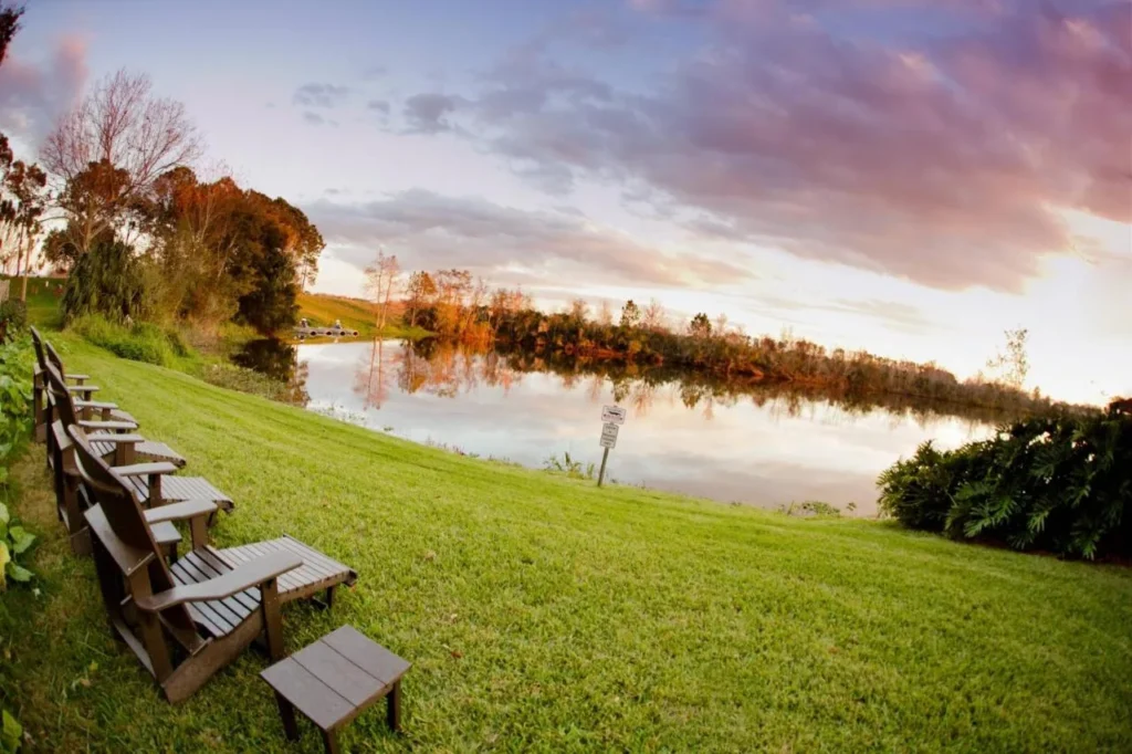 Sillas Adirondack en el c&eacute;sped frente al lago al atardecer en el Marriott Orlando Airport Lakeside