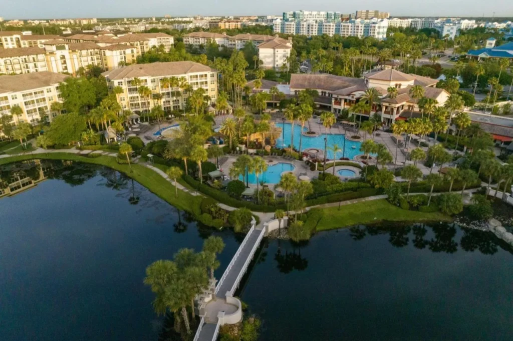 Vista a&eacute;rea de un complejo de piscina estilo laguna, lago y pasarela blanca en Sheraton Vistana Villages