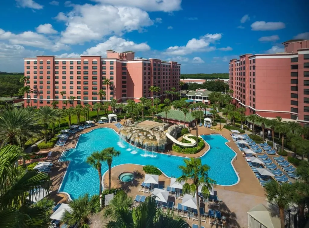Aerial view of Caribe Royale Orlando pink towers around the main pool with waterslide and cabanas
