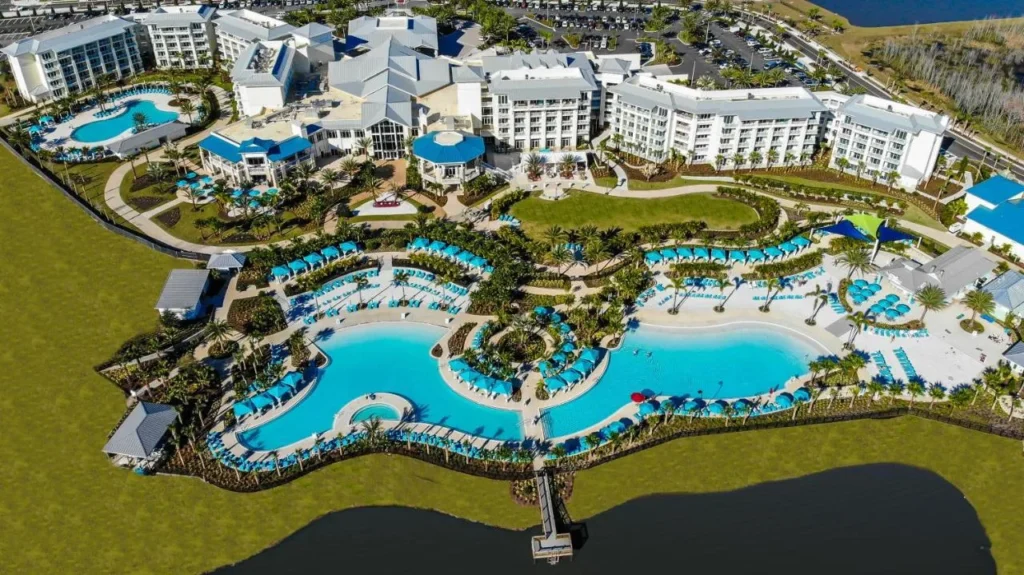 Vista a&eacute;rea de piscinas estilo laguna y edificios de hotel junto a un lago, Margaritaville Resort Orlando