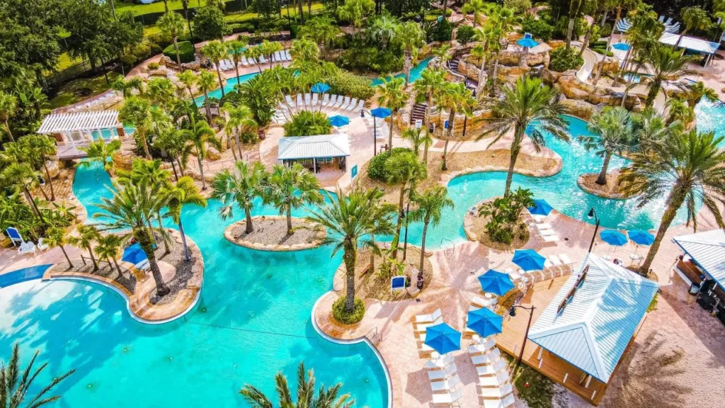 Vista aérea de piscinas bordeadas de palmeras, sombrillas y un tobogán en Reunion Resort
