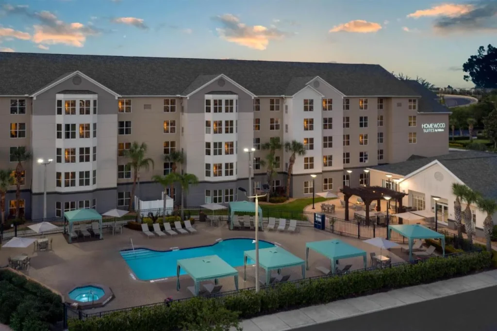 Aerial view of pool, cabanas and suite building at dusk, Homewood Suites Nearest to Universal