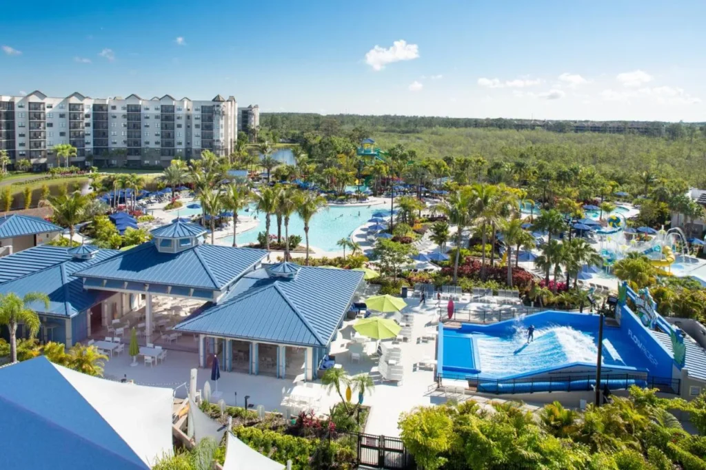 Vista aérea de la torre de invitados, piscinas y FlowRider con bosques más allá en The Grove Resort