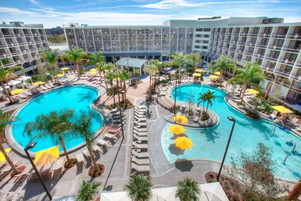 Aerial view of two palm-lined pools with yellow umbrellas at Sheraton Lake Buena Vista Resort