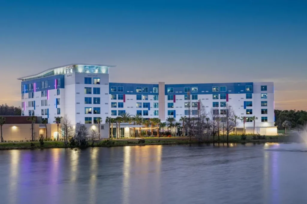 Aloft Orlando Lake Nona building lit at dusk, reflected in the lake in front