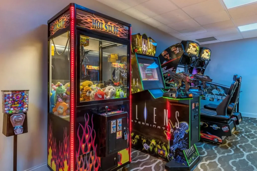 Sala de juegos arcade con m&aacute;quina de garras y juegos de carreras en Comfort Suites Maingate East
