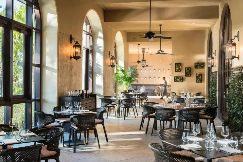 Comedor arqueado con sillas de mimbre, linternas de pared y ventiladores de techo en Four Seasons Resort Orlando