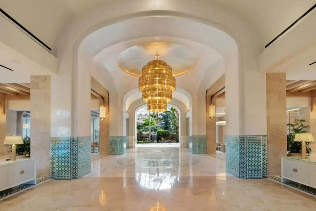 Pasillo del vestíbulo arqueado con una araña de oro y piso de mármol en Gaylord Palms Resort