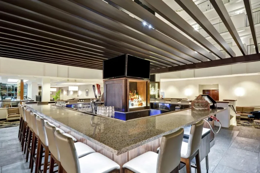 Atrium bar with stone counter and stools under a pergola at Embassy Suites Orlando Downtown