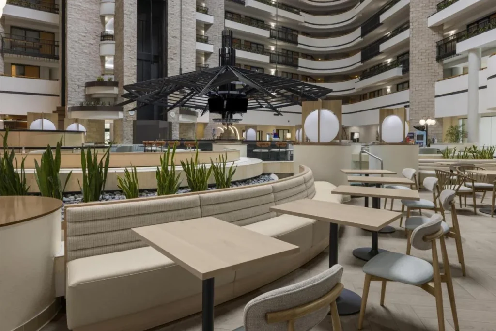 Mesas de comedor en el atrio y asientos para banquetes cerca del bar redondo en Embassy Suites ICON Park