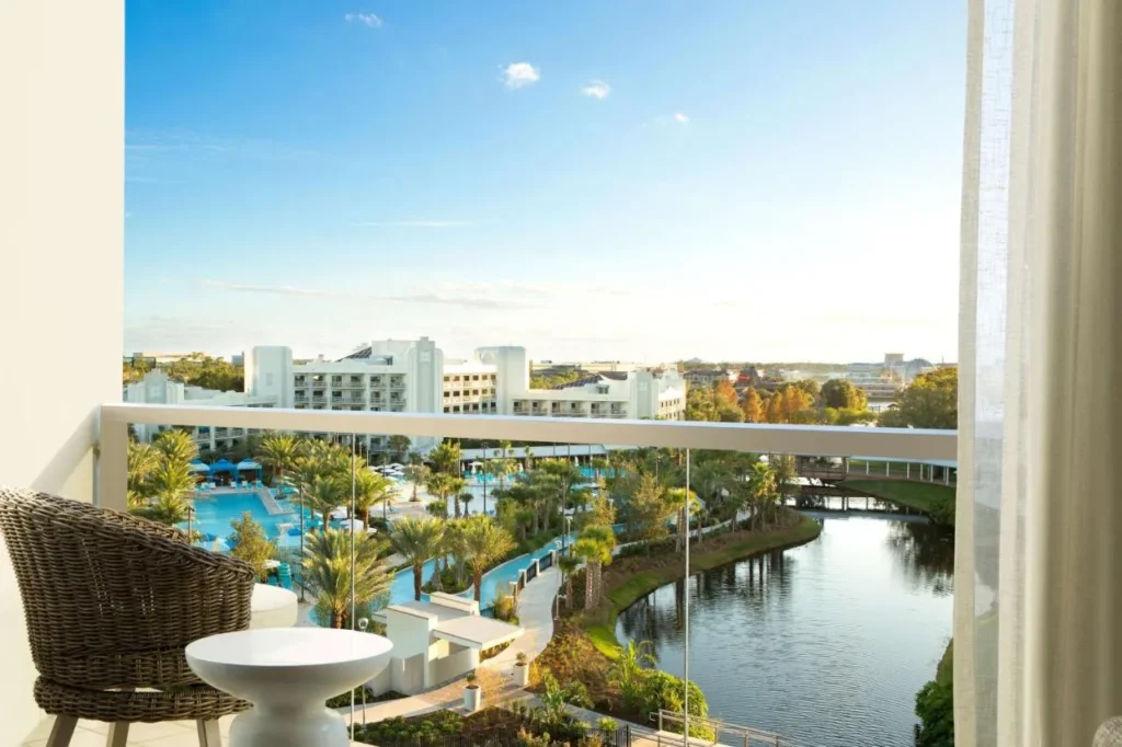 Silla de balc&oacute;n con vistas a las piscinas, palmeras, una v&iacute;a fluvial y pasarela en el Hilton Orlando Buena Vista Palace