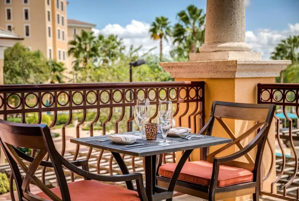 Mesa de comedor de balc&oacute;n con sillas acolchadas de naranja con vistas a las palmeras en Rosen Shingle Creek