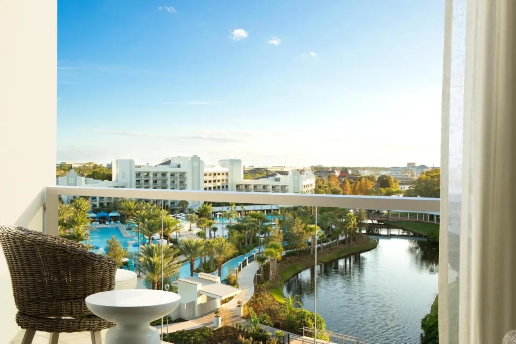 Balcony with a wicker chair overlooking the pools and waterway at Hilton Orlando Buena Vista Palace