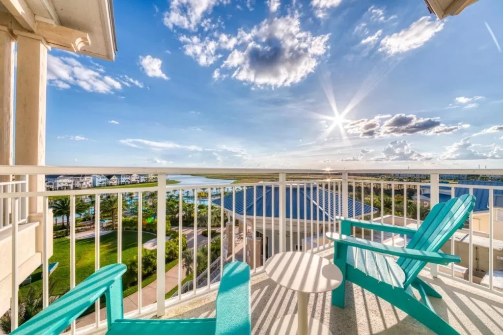 Balcony with turquoise Adirondack chairs overlooking the pool area, cottages and lake at Margaritaville Resort Orlando