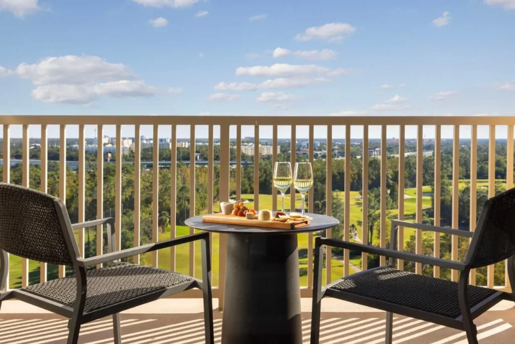 Balcón con dos sillas y una mesa de bistro con vistas al campo de golf en Waldorf Astoria Orlando