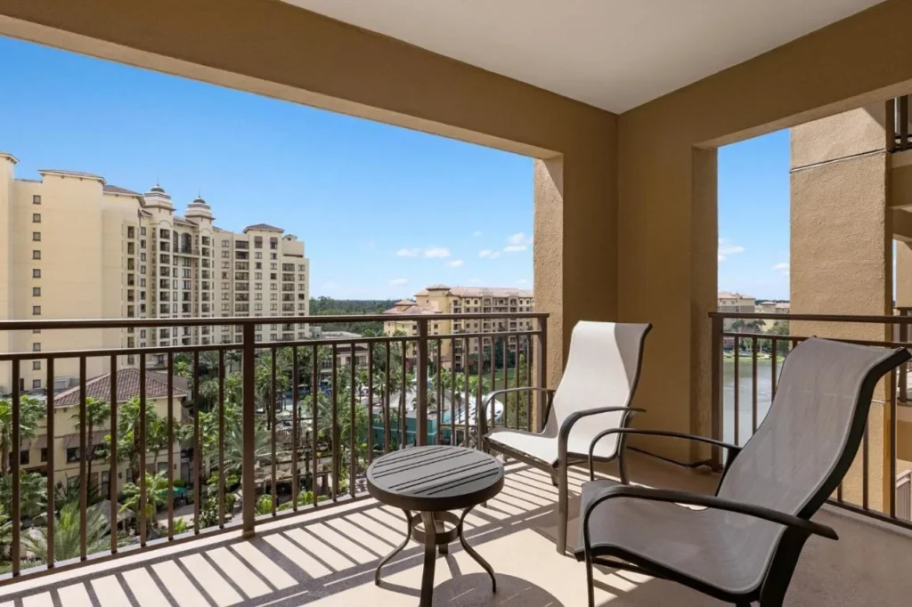 Balc&oacute;n con dos sillas con vistas a las torres del complejo y jardines bordeados de palmeras en Club Wyndham Bonnet Creek