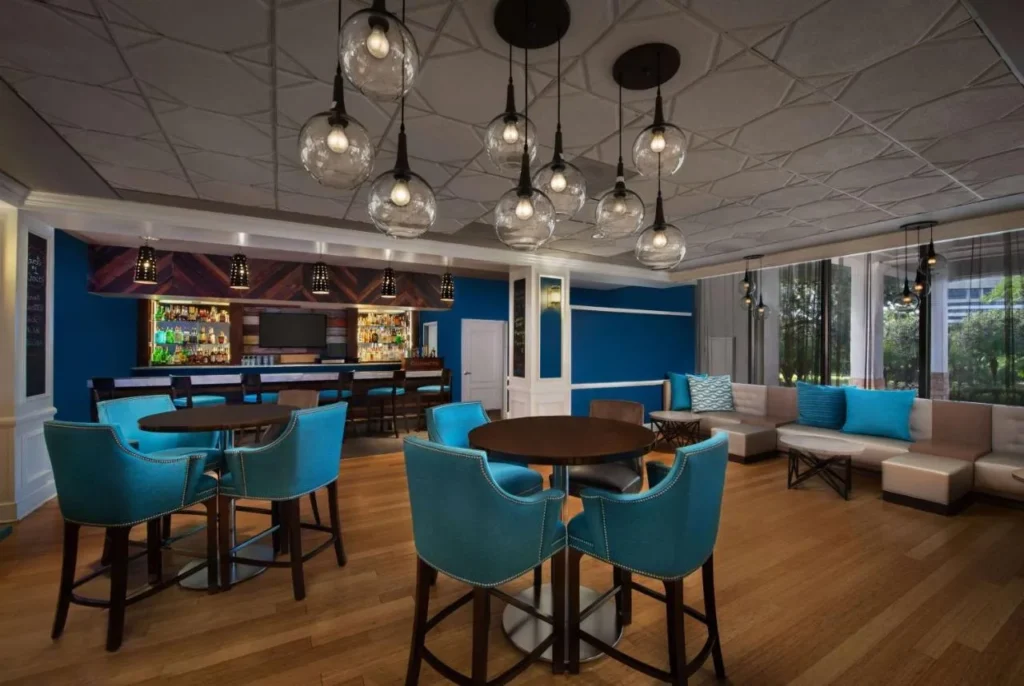 Sal&oacute;n de bar con sillas altas azules y luces colgantes en Wyndham Garden Lake Buena Vista