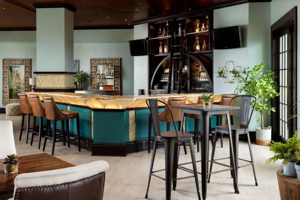 Bar with a lit stone counter, leather stools and high-top tables at Reunion Resort