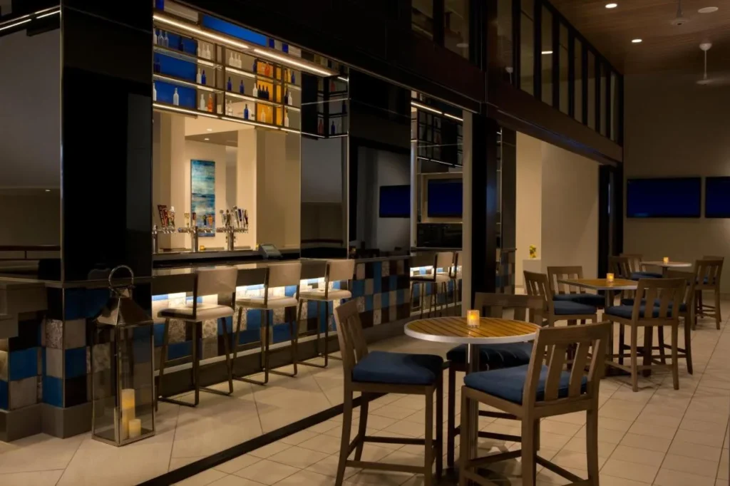 Bar con mesas altas y estantes de botellas retroiluminados en el Hilton Orlando Buena Vista Palace