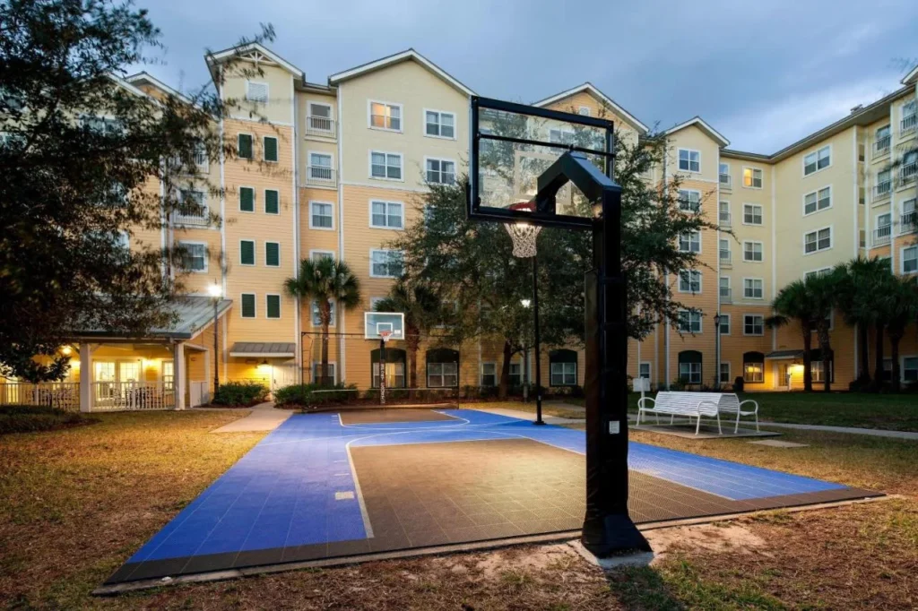 Cancha deportiva de baloncesto al lado de los edificios de habitaciones amarillos en el Residence Inn Orlando at SeaWorld