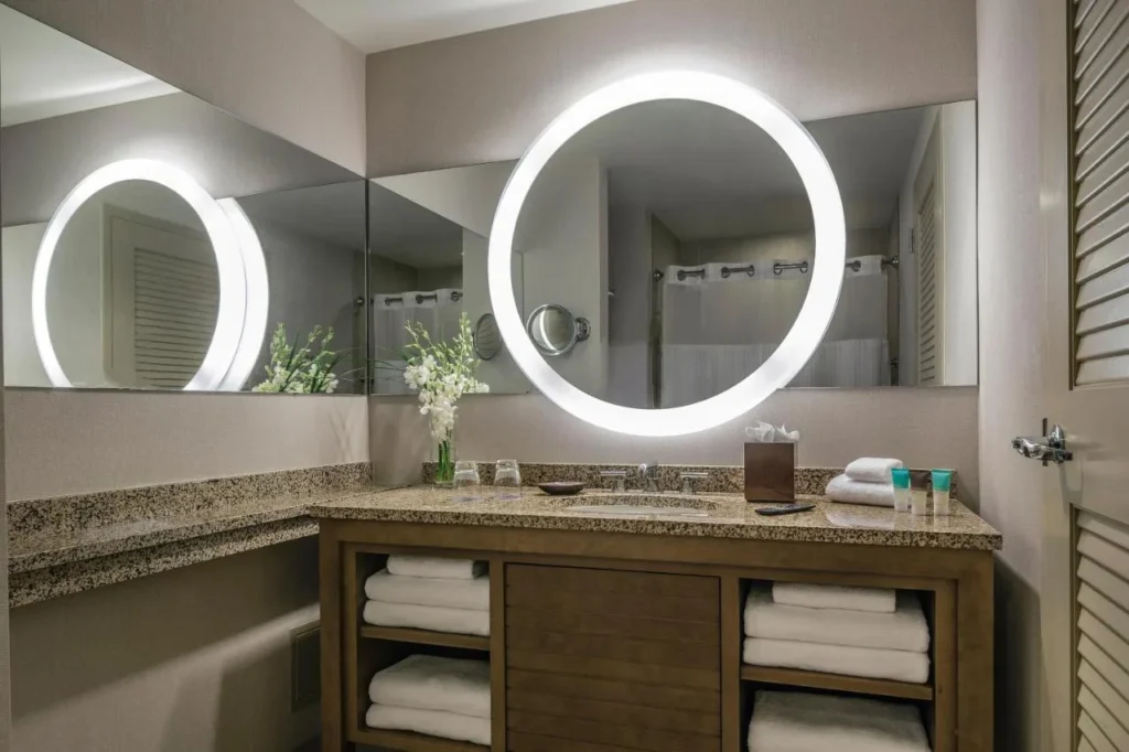 Bathroom vanity with a lit round mirror and stacked towels at Hyatt Regency Orlando