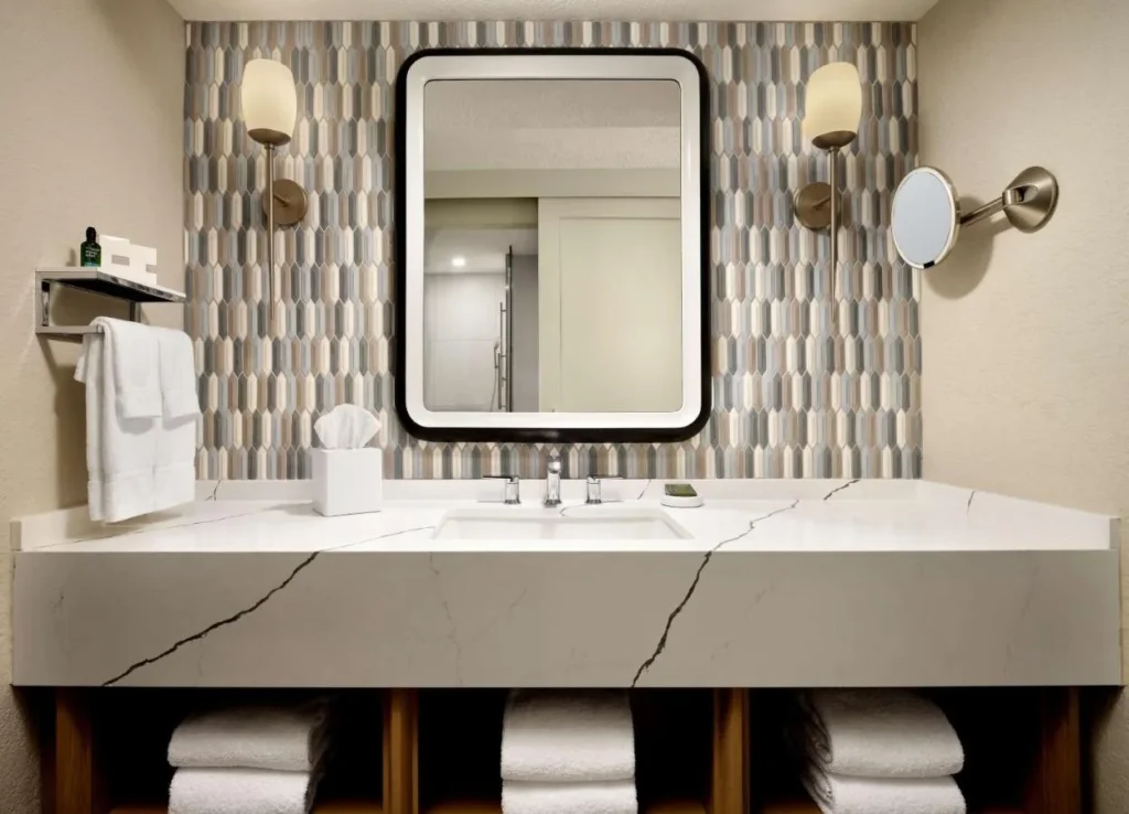Tocador de ba&ntilde;o con encimera de piedra, protector antisalpicaduras de azulejos y espejo enmarcado en Caribe Royale Orlando
