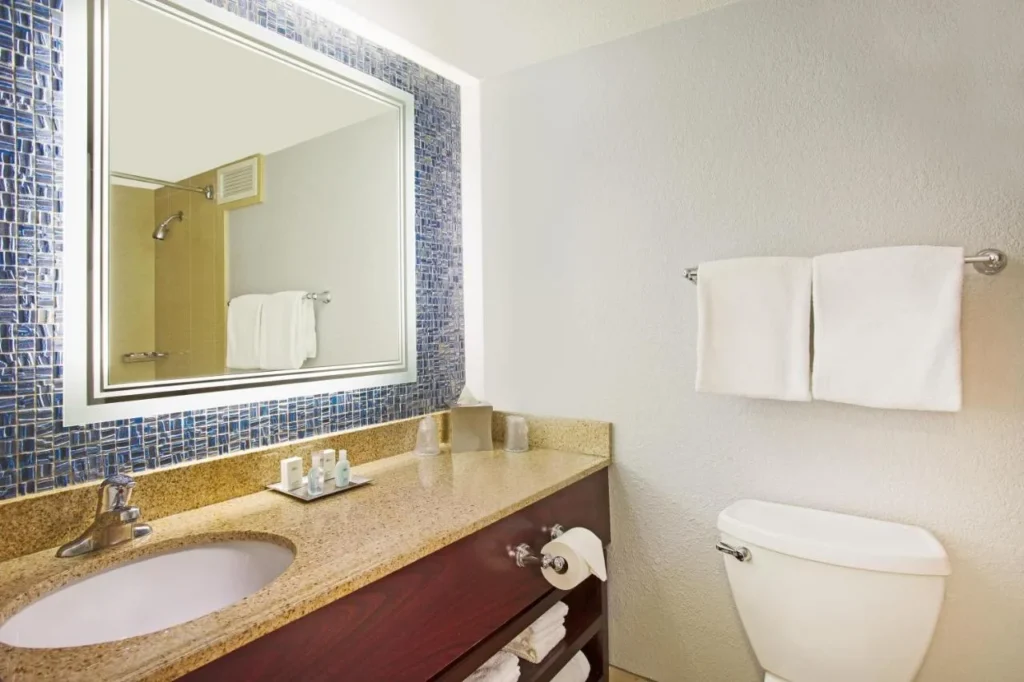Cuarto de ba&ntilde;o con espejo retroiluminado y mosaicos azules en Wyndham Lake Buena Vista