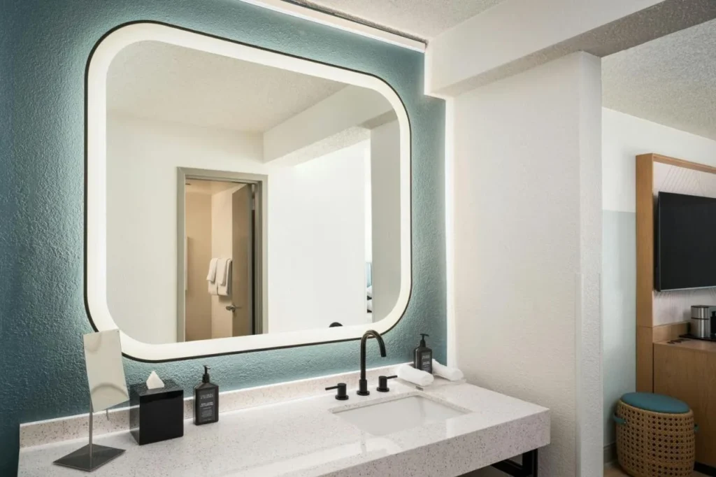 Cuarto de ba&ntilde;o con espejo retroiluminado y mostrador de piedra en Sheraton Lake Buena Vista Resort