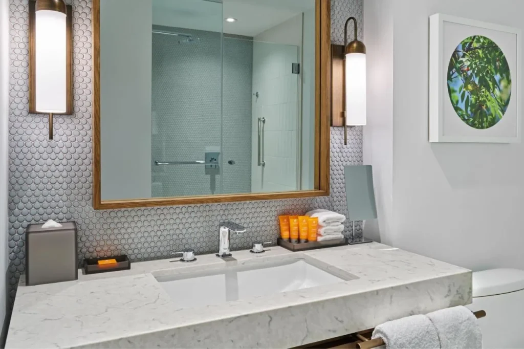 Bathroom vanity with penny-tile wall, wood mirror and glass shower at Walt Disney World Swan Reserve
