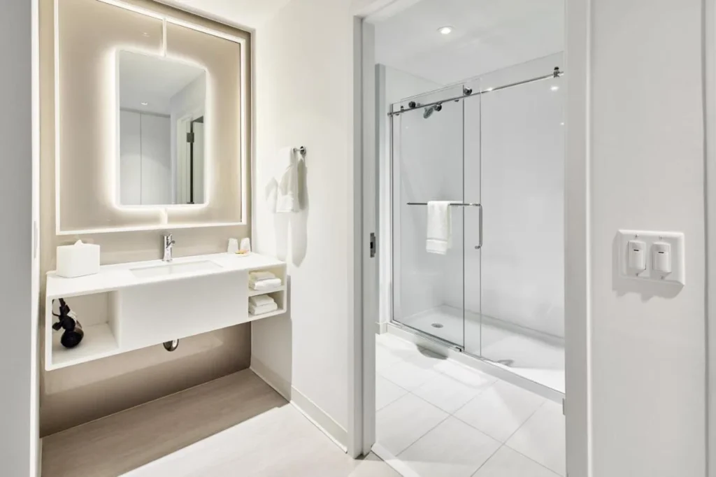 Cuarto de baño con espejo retroiluminado, tocador flotante y ducha con puerta de cristal en Universal Terra Luna Resort
