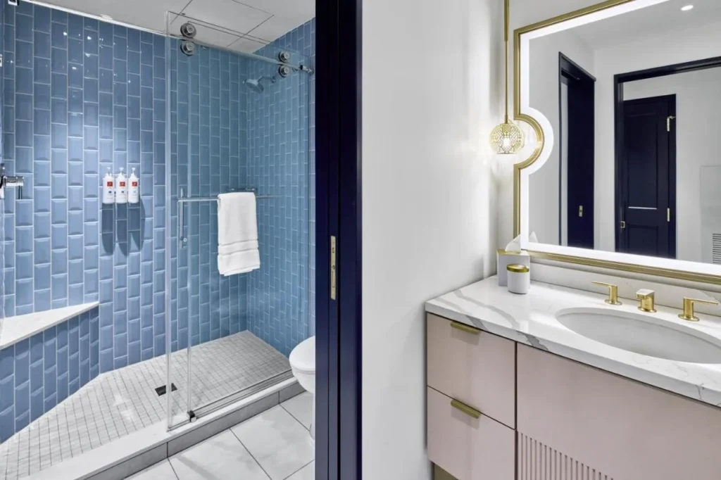 Bathroom with a blue-tiled walk-in shower and pink marble-top vanity at Universal Helios Grand Hotel