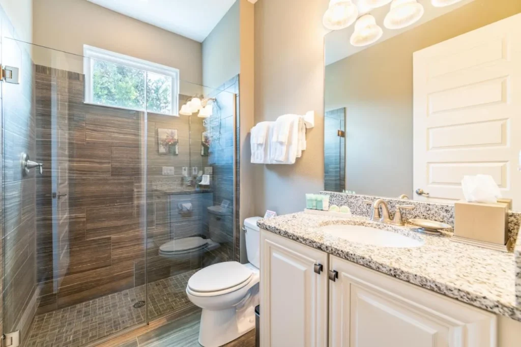 Cuarto de baño con una ducha de cristal y un tocador de granito en una casa Encore Resort