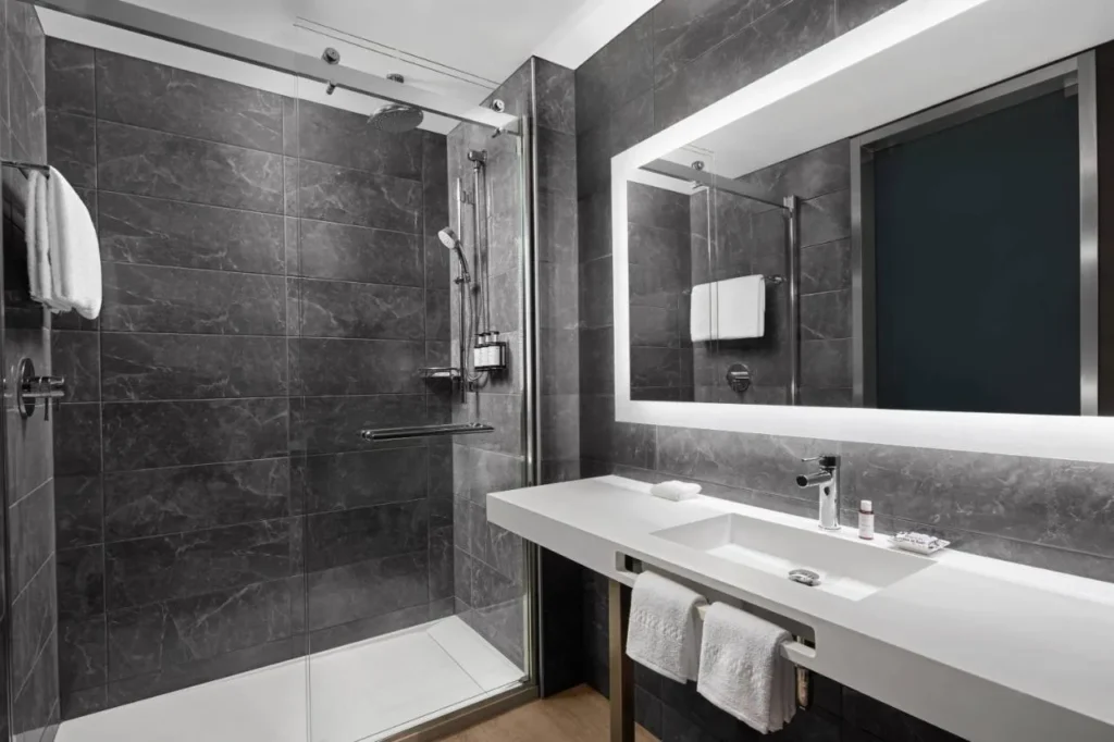 Cuarto de baño con ducha a ras de suelo y espejo iluminado en el AC Hotel Orlando Downtown