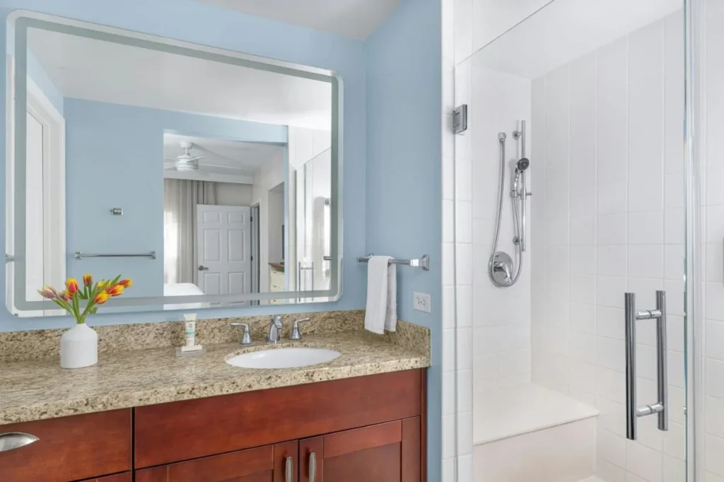 Cuarto de baño con tocador de granito y ducha a ras de suelo con puerta de vidrio en Marriott's Harbour Lake