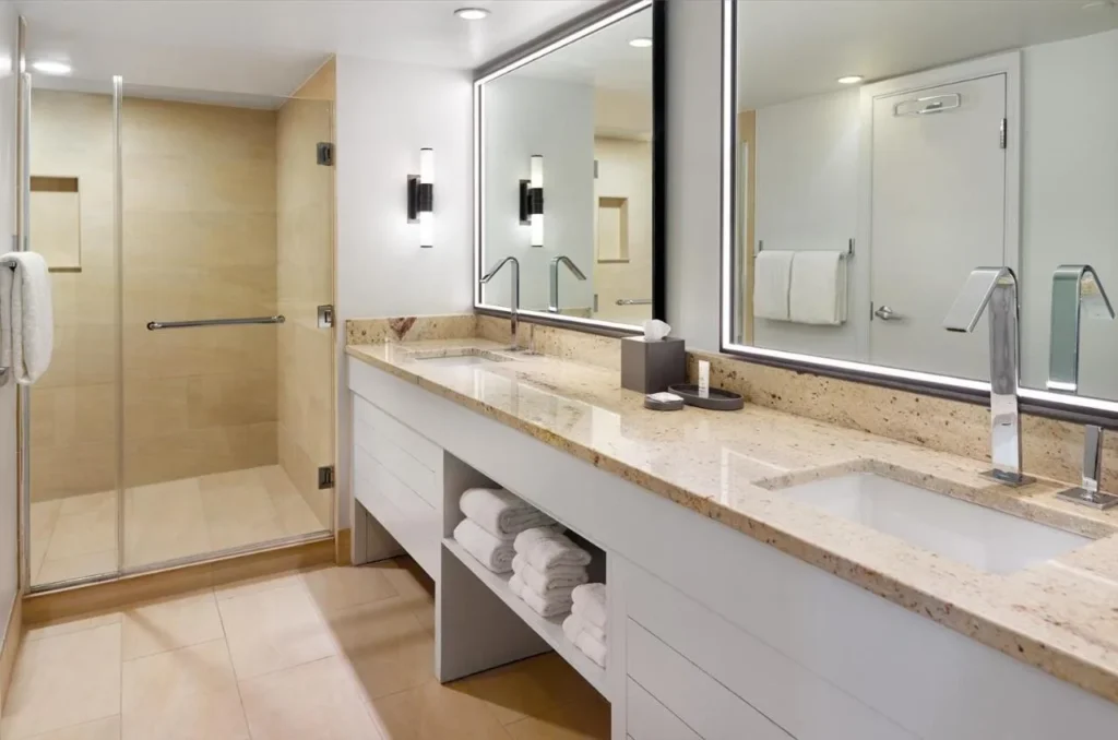 Cuarto de ba&ntilde;o con tocador doble largo y ducha a ras de suelo de vidrio en el Orlando World Center Marriott