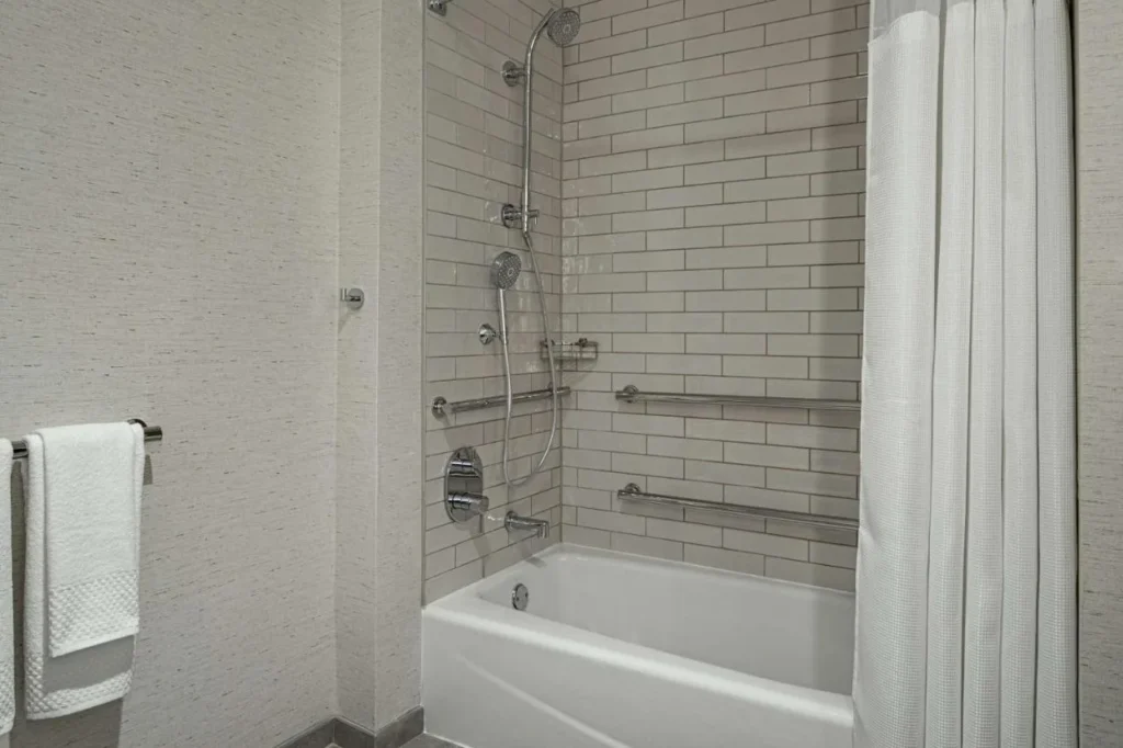 Cuarto de ba&ntilde;o con ba&ntilde;era, barras de apoyo y ducha de mano en DoubleTree Suites Disney Springs