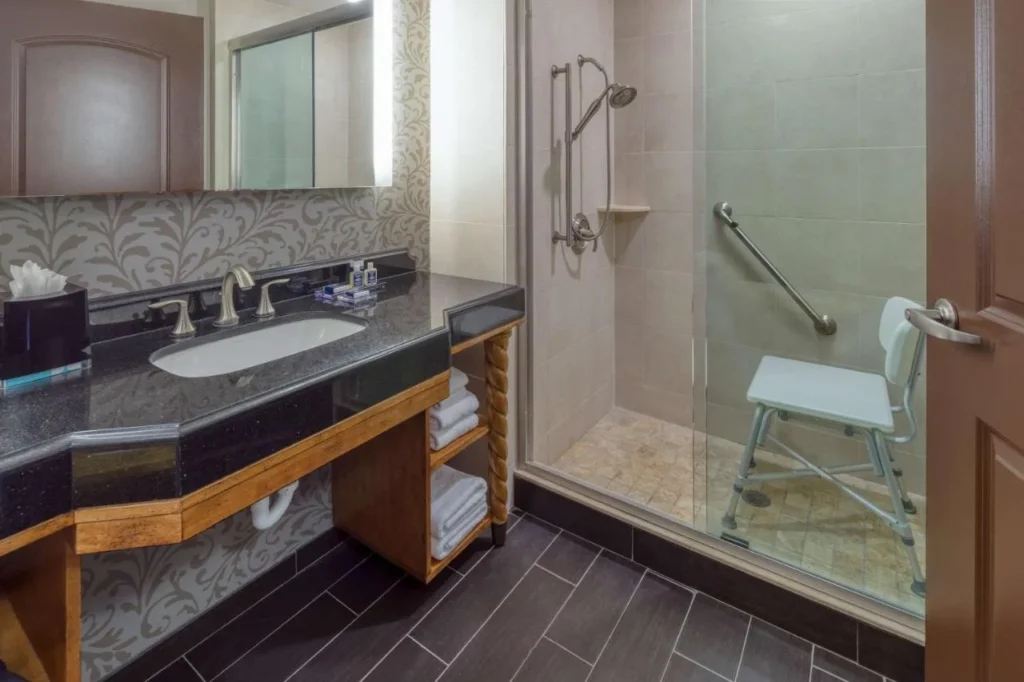 Cuarto de baño con tocador de piedra oscura y ducha de cristal a pie en Wyndham Grand Orlando Bonnet Creek